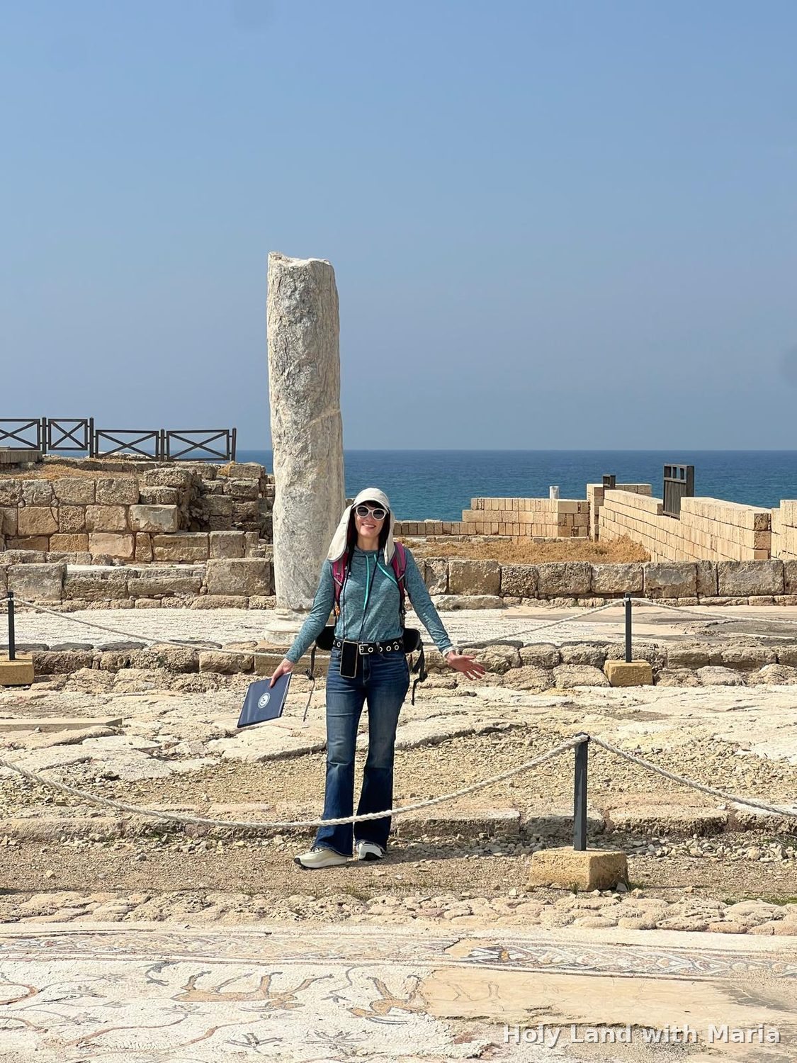 Maria Lando beside a Roman column at Caesarea, with the Mediterranean behind