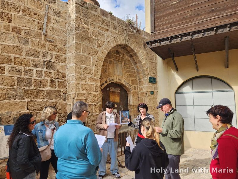 Guests on the Jaffa tour looking at historical photographs outside an old stone house