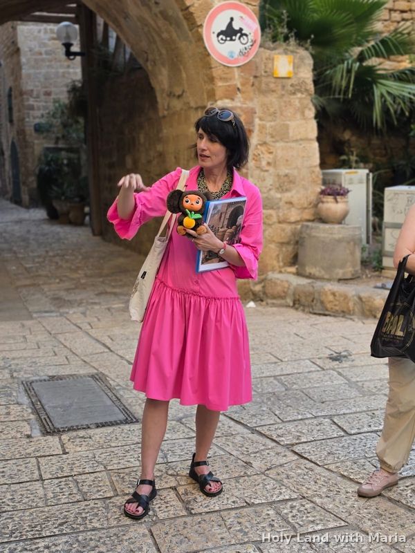 Maria Lando guiding in a lane of Old Jaffa, holding historical photographs