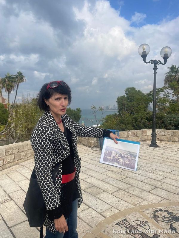 Maria Lando showing a historical photograph on a terrace in Old Jaffa
