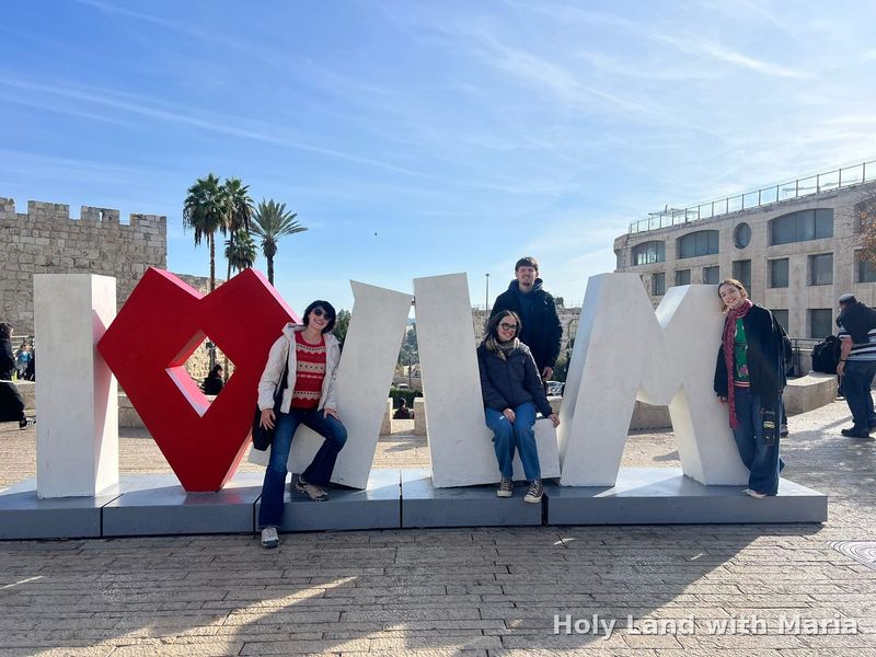 Maria Lando and her guests at the I Love Jerusalem sign beside the Old City walls