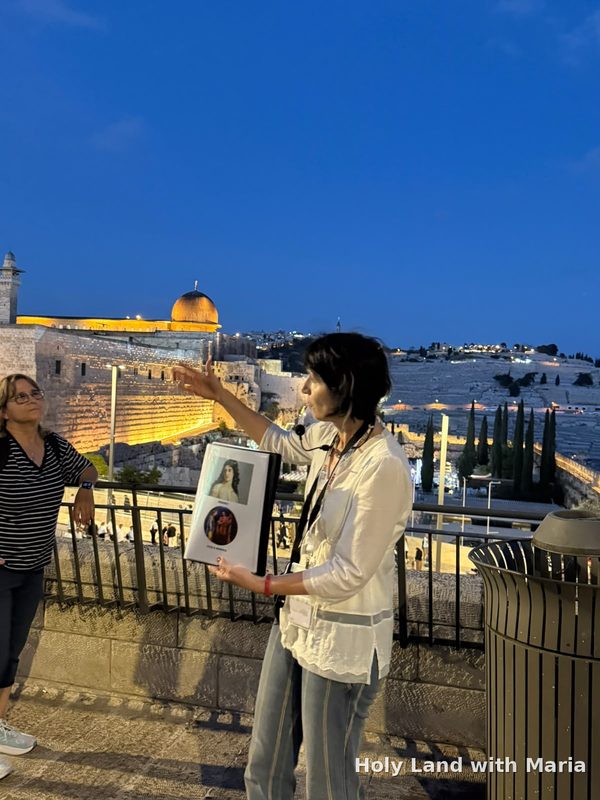 Maria Lando telling the story of Julia Berenice at the lookout above the Western Wall, with Al-Aqsa Mosque and the Mount of Olives behind her at dusk