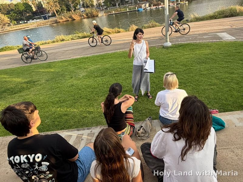 Maria Lando guiding a seated group in Hayarkon Park, Tel Aviv